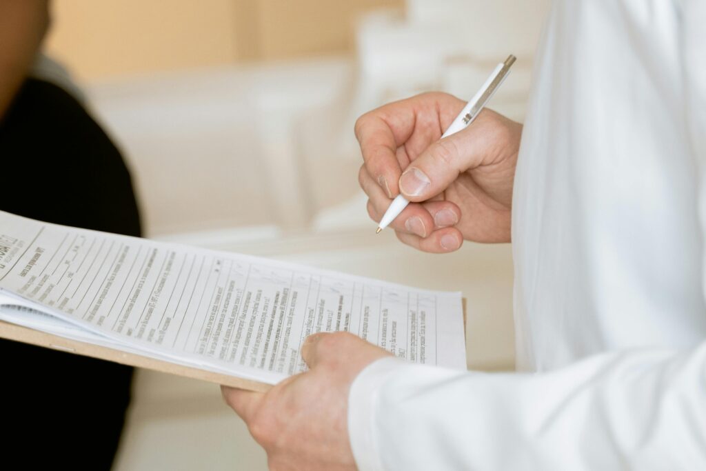Two individuals reviewing and signing a document, one holding a pen.