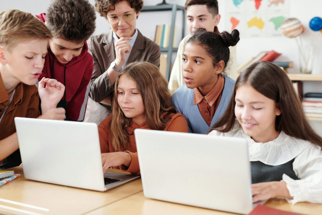 Students with laptops engaged in group work at a classroom table.