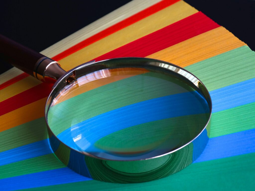 Magnifying glass on multicolored striped background.