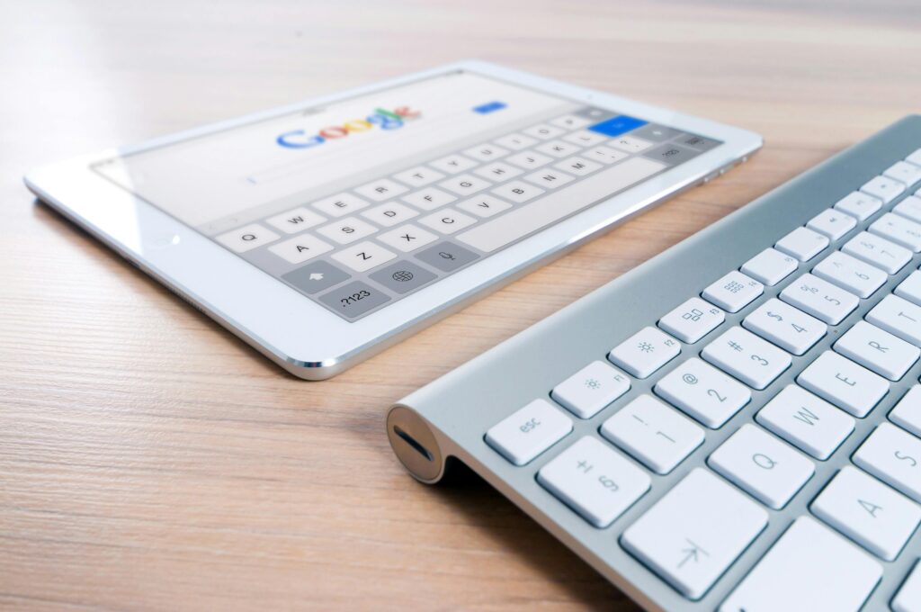 Tablet with Google homepage on screen next to a wireless keyboard.